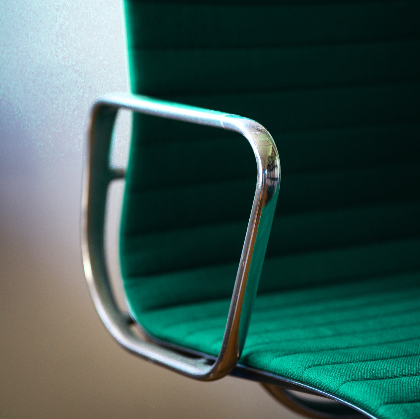 Close-up of a chair and glass table edge, in Forge's cool teal palette.